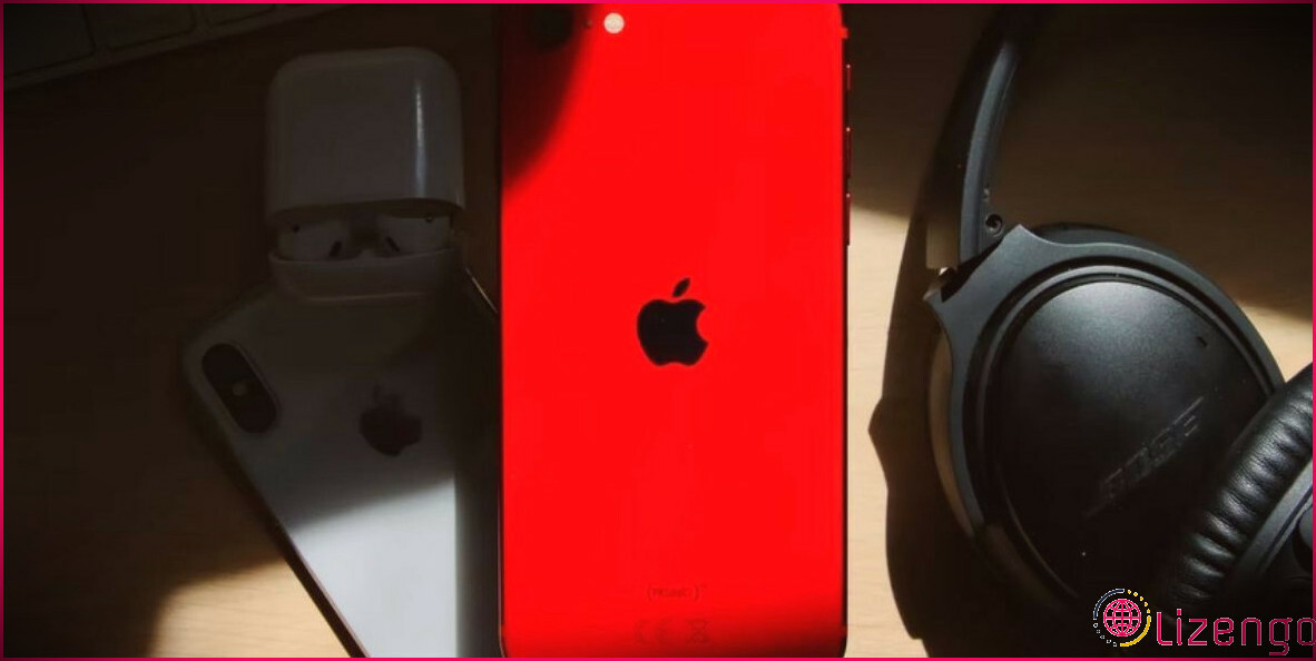 iphone 7 rouge à côté d'un casque noir sur un bureau en bois