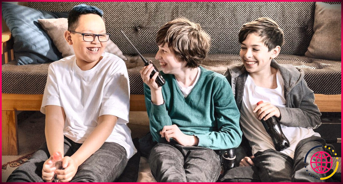 Trois enfants rient en utilisant un talkie-walkie
