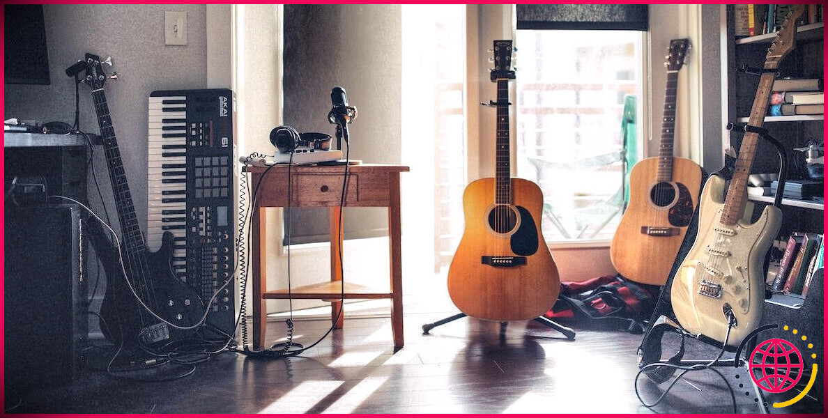 Guitares acoustiques et électriques à côté d'un microphone et d'un casque sur une table.