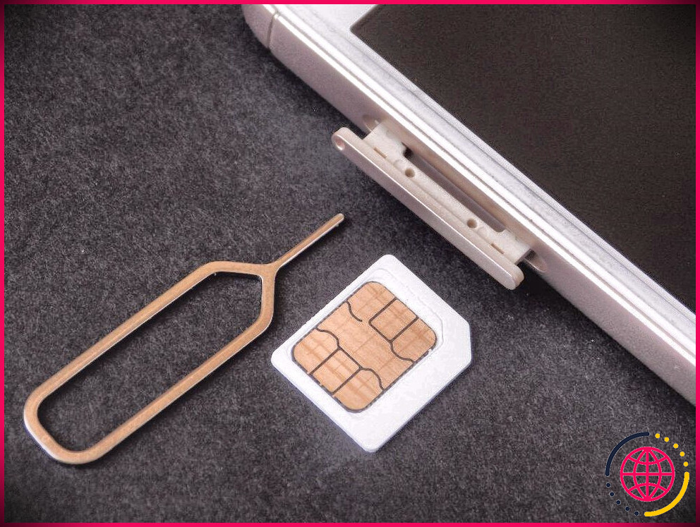Une carte SIM et un éjecteur, à côté d'un iPhone
