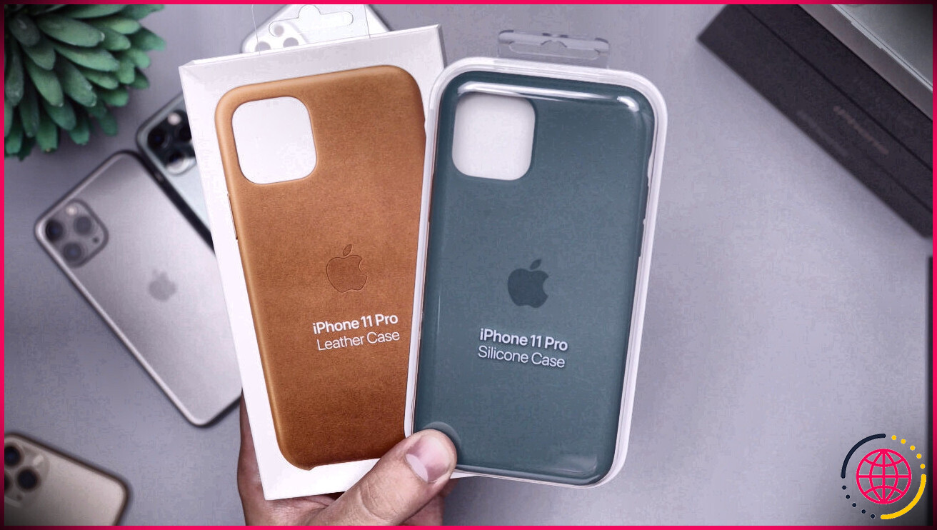 Une main tient deux coques pour iphone : une en cuir et une en silicone.