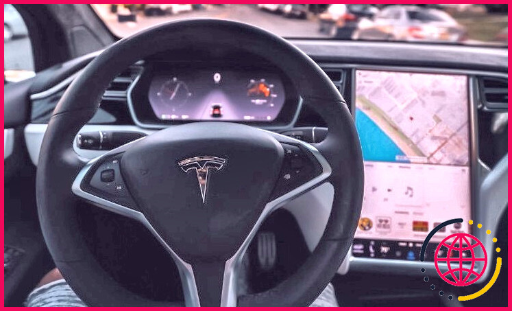 personne conduisant une Tesla autonome sans les mains sur le volant