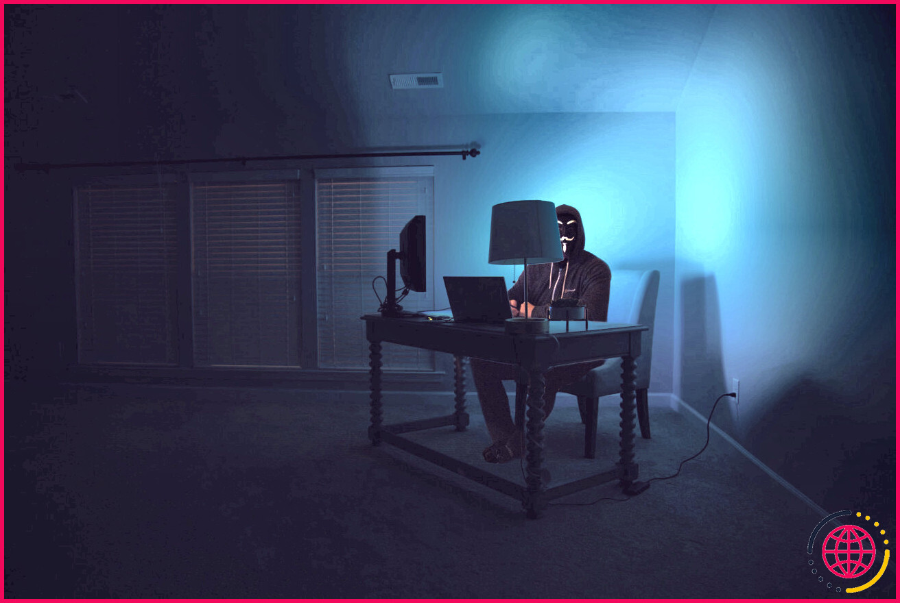 Photo d'un hacker assis devant un ordinateur 