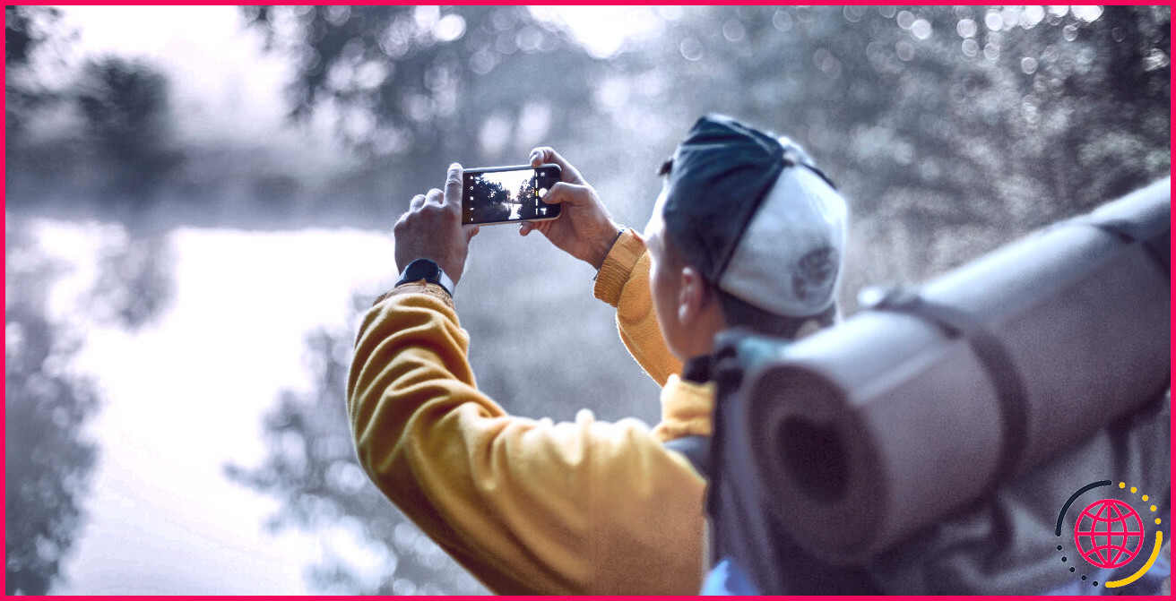 homme utilisant un smartphone pour prendre une photo du lac